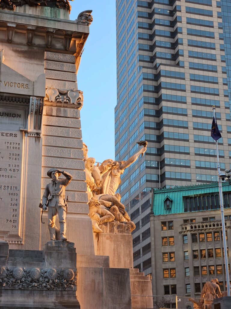 Close-up of a veteran monument and a soldier with his up in a salute. The side profile shows Lady Liberty and soldiers in fight.