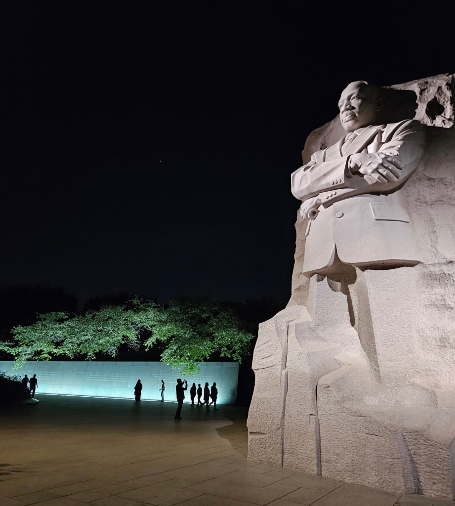 MLK Jr. Monument at night showing the memorial in full with the silhouettes of visitors at his quote walls.